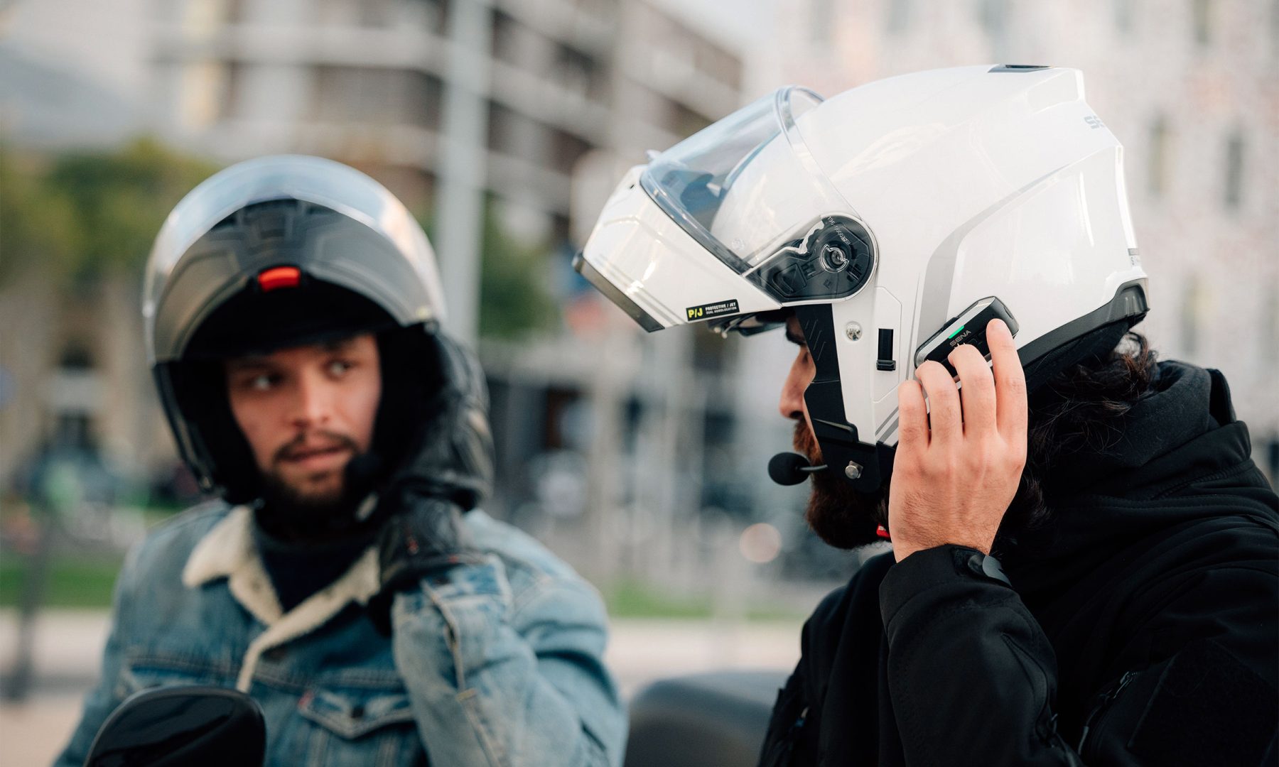 Two riders wearing Sena Outrush 2 Mesh modular helmets using built-in communication system