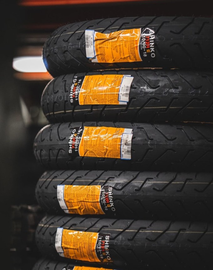 Stack of Shinko 712 cruiser tires with orange labels in a shop setting