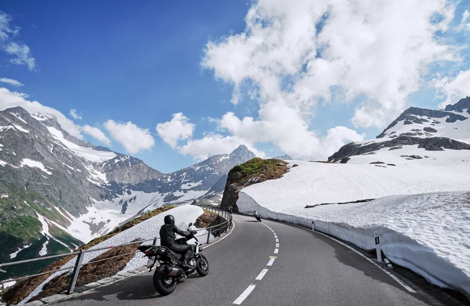 Motorcyclists riding through snowy mountain roads, illustrating the challenges of cold-weather riding conditions