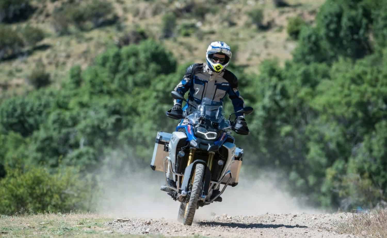 Adventure touring rider on a BMW GS bike kicking up dust on a rugged trail, showcasing durability and performance with Liqui Moly oil