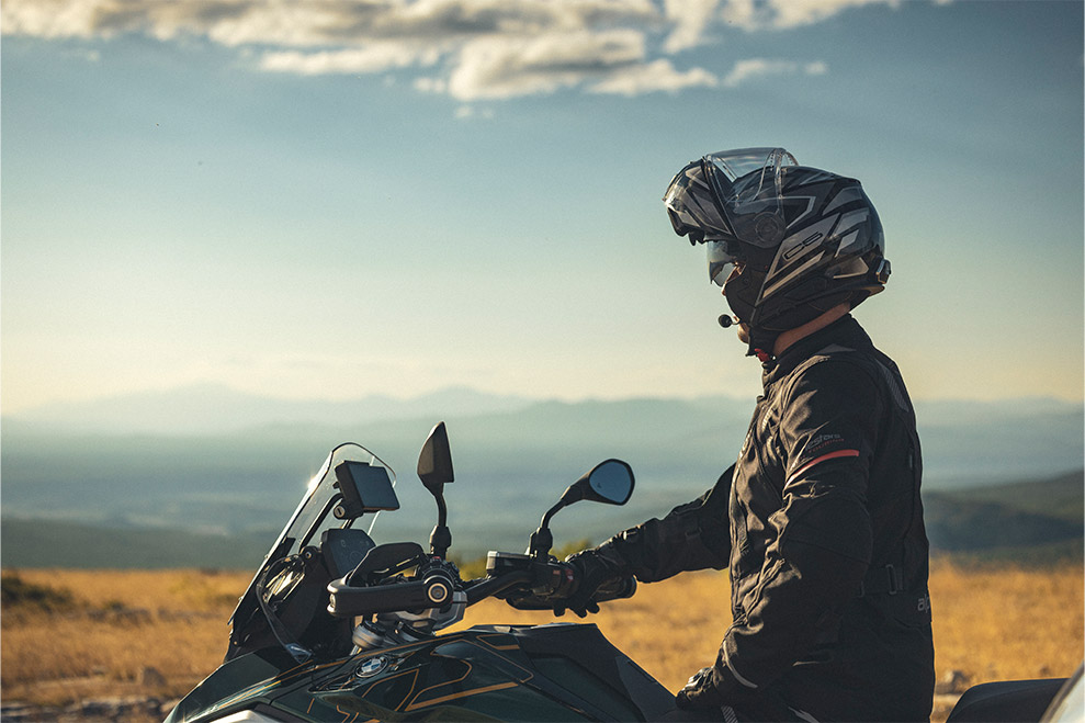 Rider wearing a Schuberth C5 helmet on a touring motorcycle with scenic mountains in the background