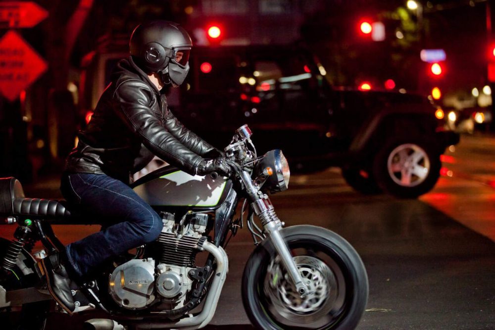 Motorcyclist riding through city streets at night on a Kawasaki, showcasing durability and reliability with Shell Rotella T6 oil