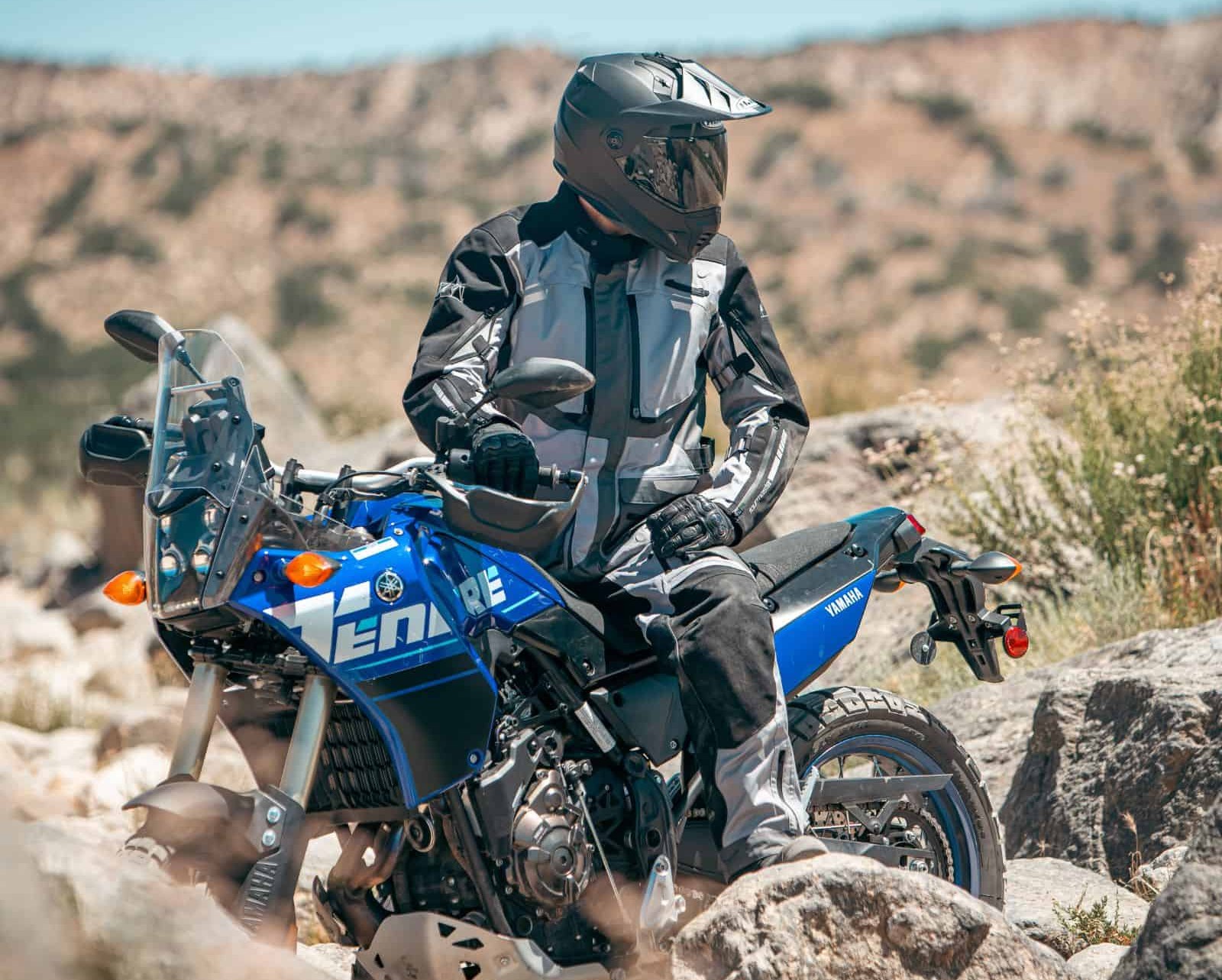 Rider wearing Tourmaster Highlander waterproof jacket on Yamaha Tenere in rocky terrain