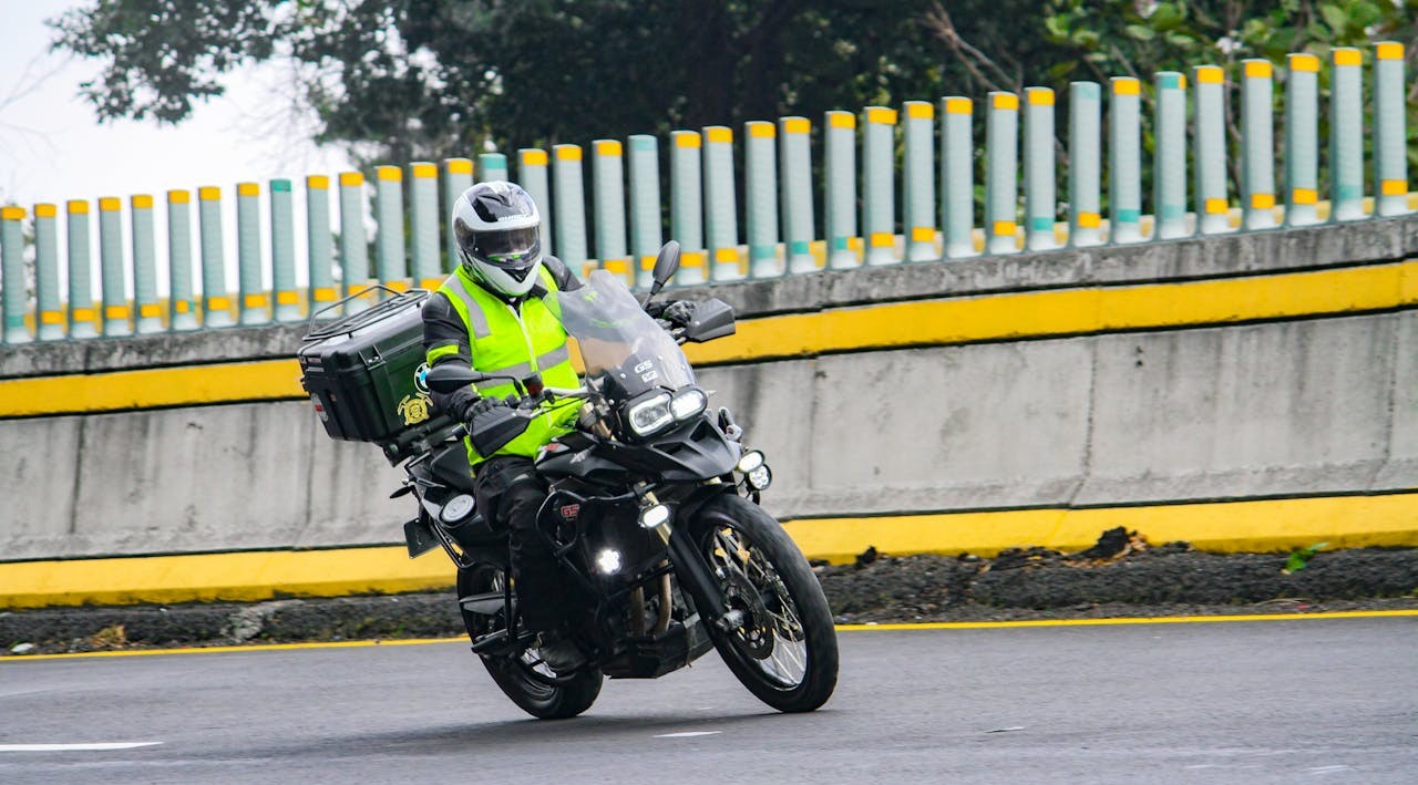 Motorcyclist in a bright hi-viz vest riding through a curve, highlighting safety over style.