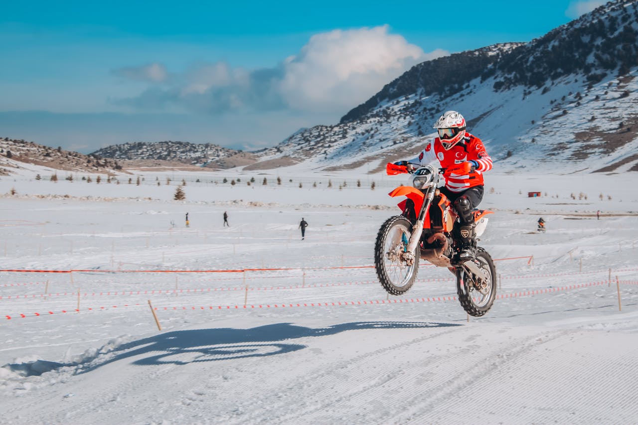 Adventure rider on a dirt bike in snowy terrain, showcasing winter motorcycle gear for off-road conditions
