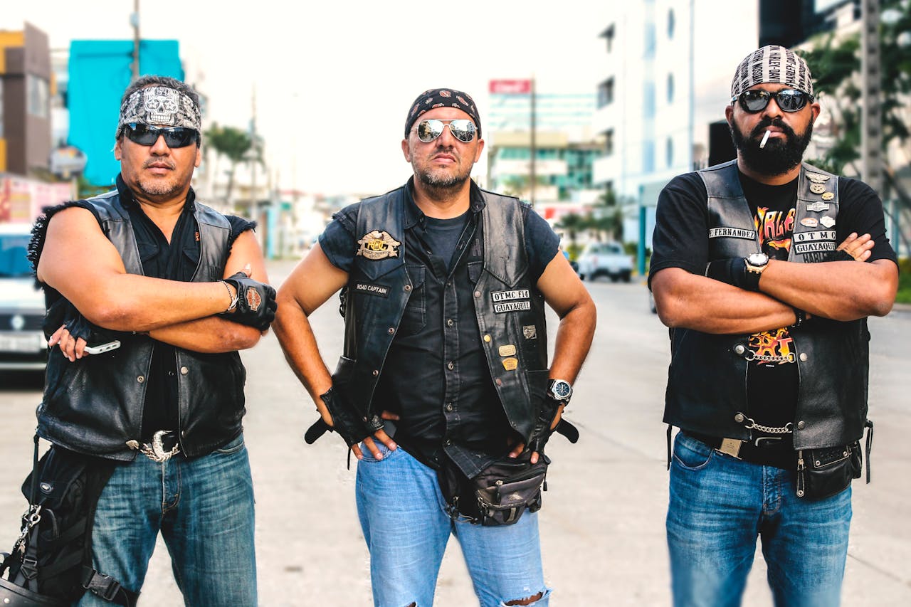 Three bikers in leather vests posing confidently, highlighting the fashion side of motorcycle gear.