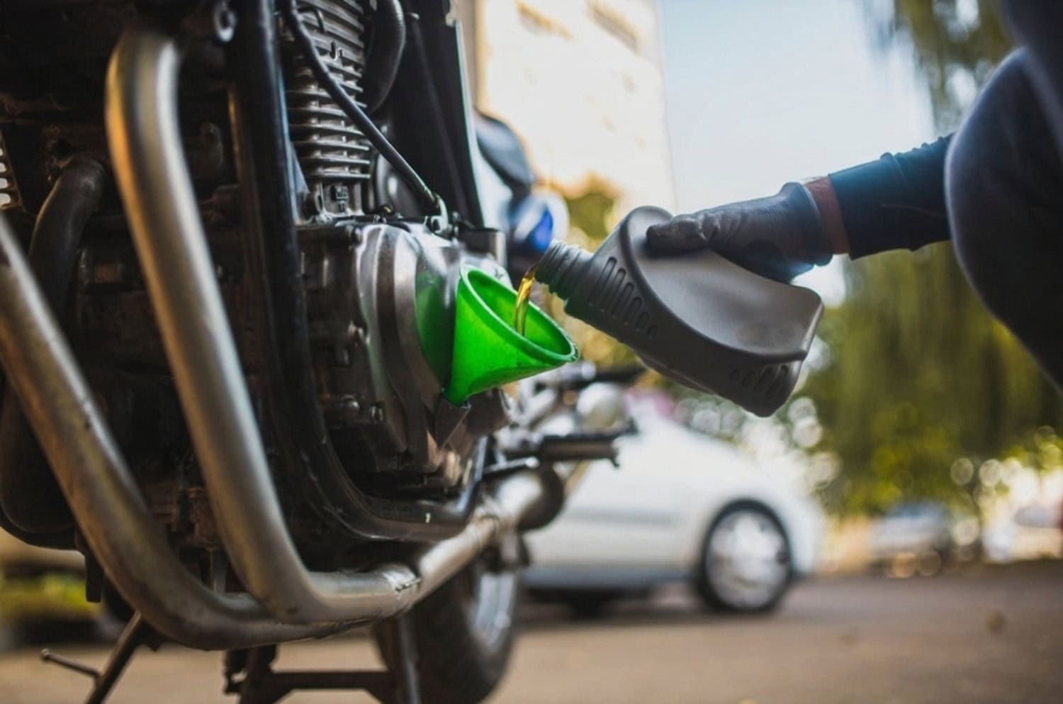 Pouring motorcycle oil into engine with funnel during maintenance