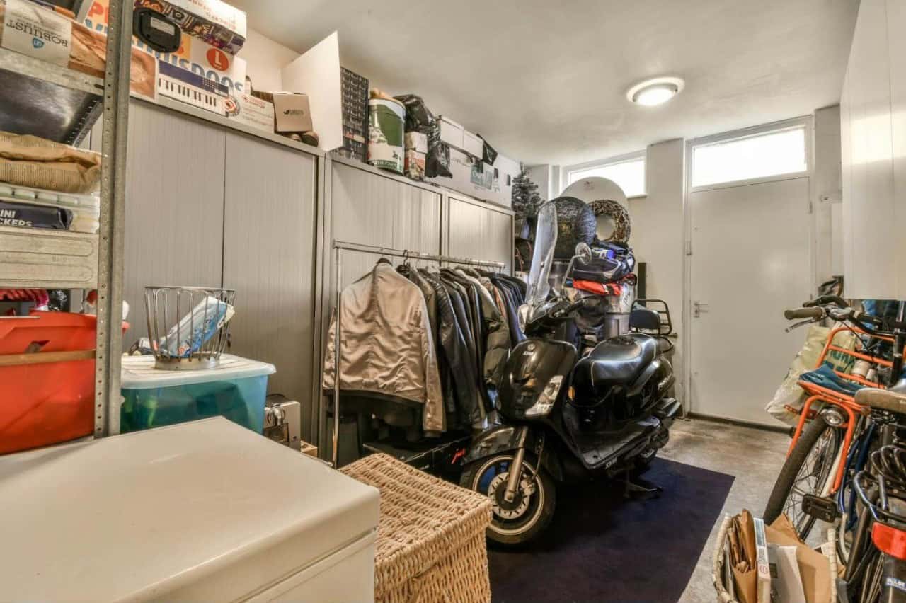 Motorcycle stored indoors for winter alongside jackets and gear.