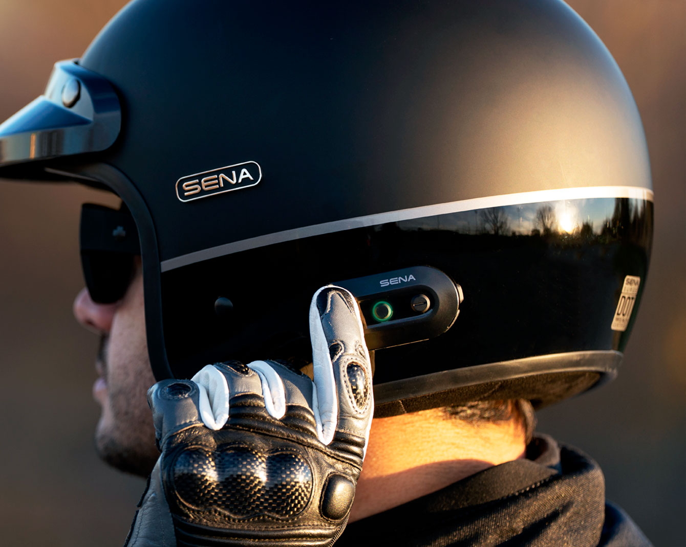 Rider using the built-in communication controls on a Sena Surge open-face helmet.