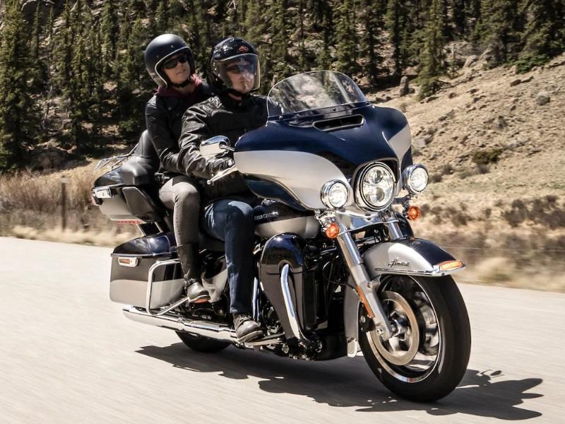Harley-Davidson touring motorcycle with rider and passenger cruising on the highway, showcasing pillion comfort and relaxed posture