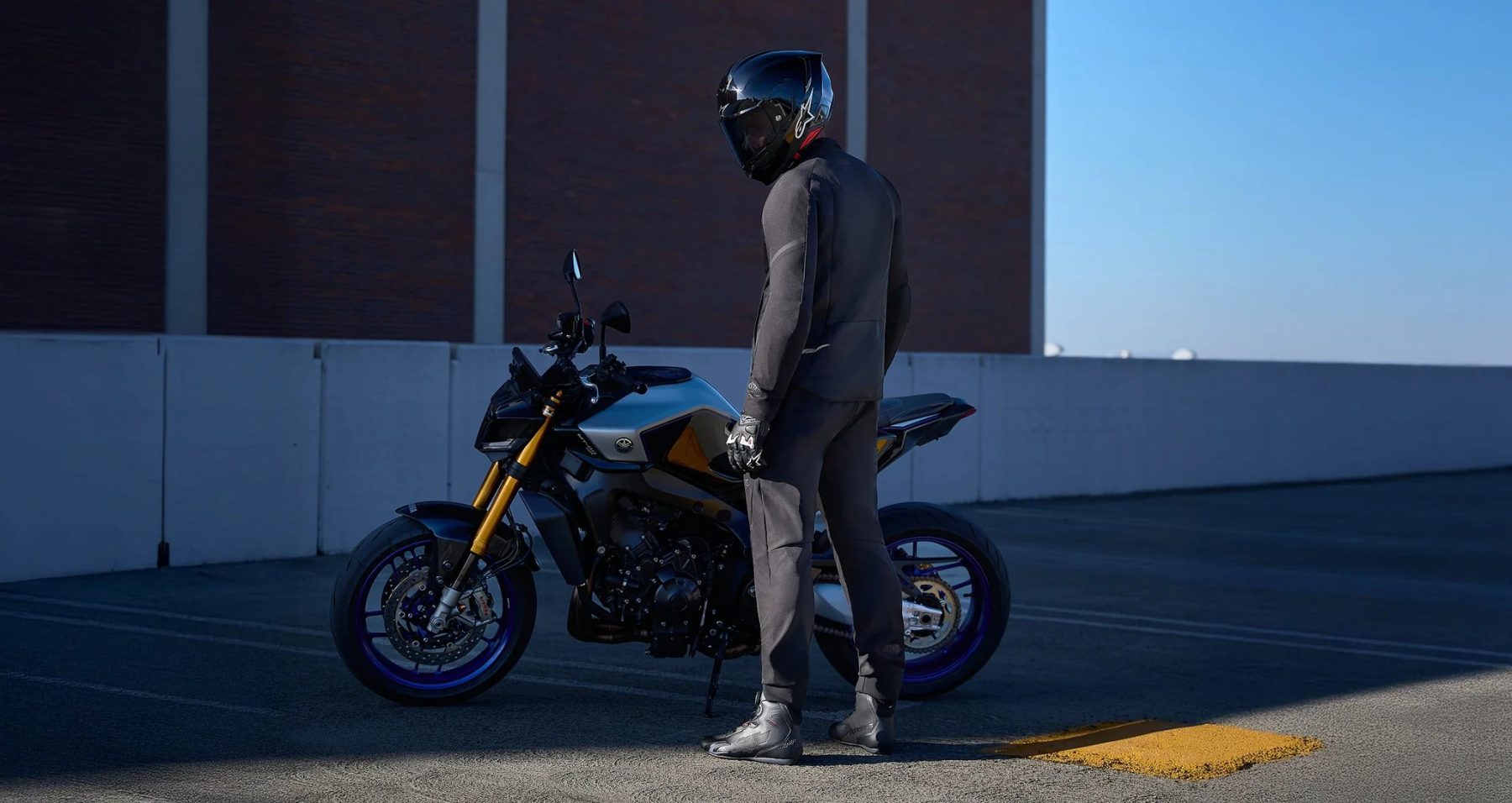 Rider wearing Alpinestars Aeroshell Airflow pants standing next to a sport motorcycle