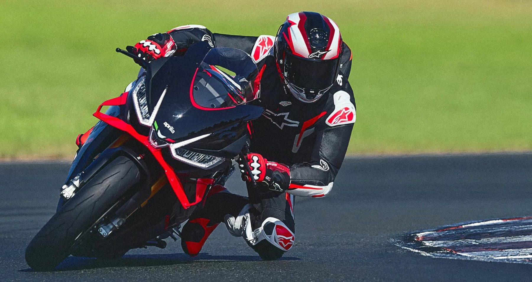 Rider wearing the Alpinestars GP Tech V5 race suit leaned into a high-speed corner on a sportbike