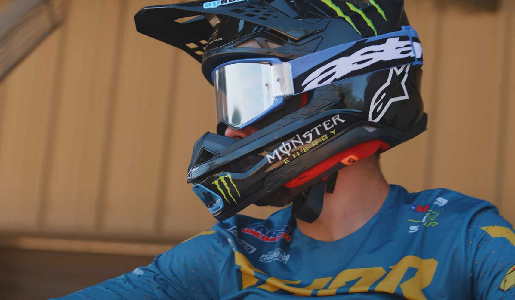 Motocross rider wearing Alpinestars goggles and Monster Energy helmet demonstrating tear-off lens system