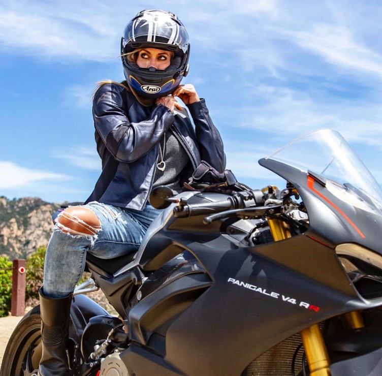 Rider wearing an Arai Corsair-X helmet on a Ducati Panigale V4 R, tightening the strap before a ride, showcasing premium sport performance.