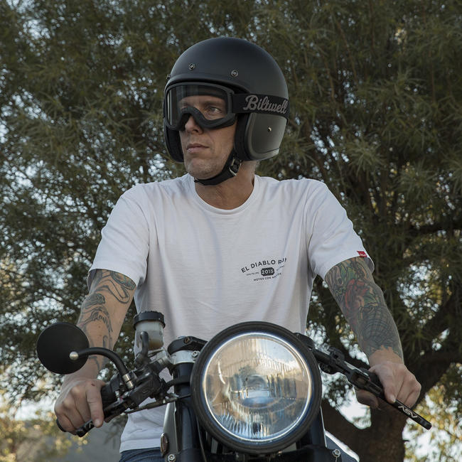 Rider wearing Biltwell Moto 2.0 goggles and open-face helmet on a café-style motorcycle