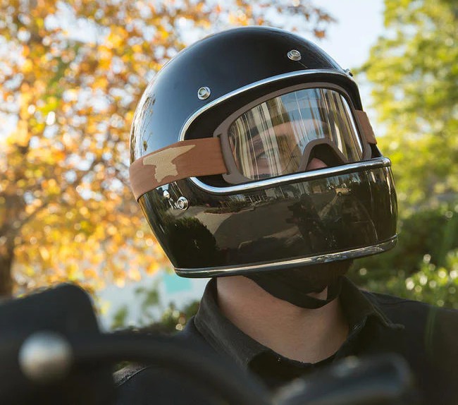 Motorcyclist wearing retro goggles and full-face helmet on a sunny day