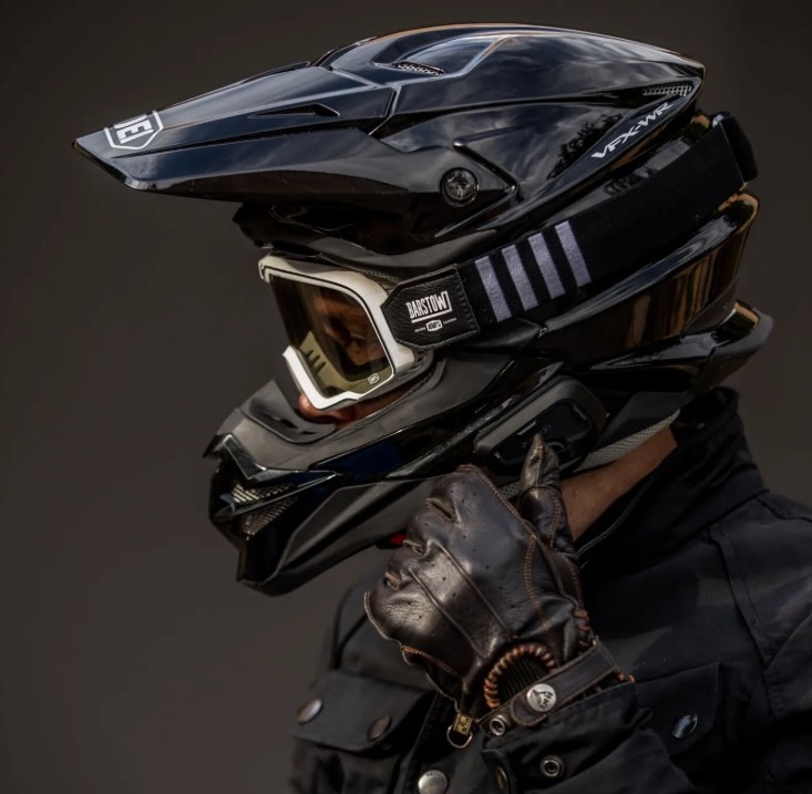 Close-up of a rider wearing a black motocross helmet with goggles and a Cardo Freecom 2X communicator mounted on the side.