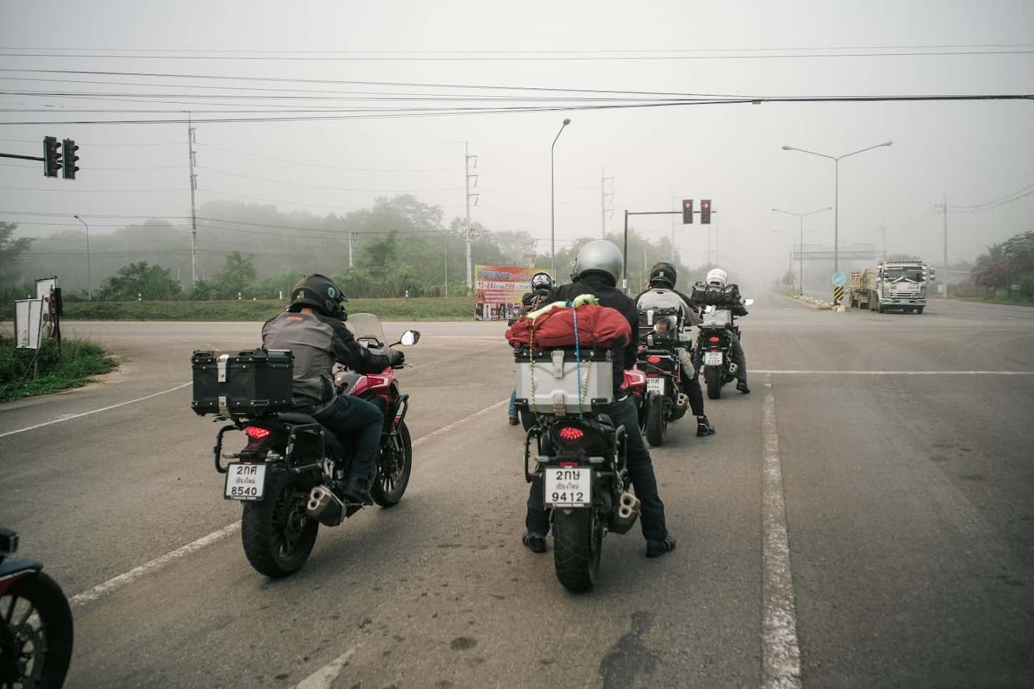 Group of motorcyclists waiting at a foggy intersection, loaded touring bikes ready for a long ride, symbolizing different riding styles.
