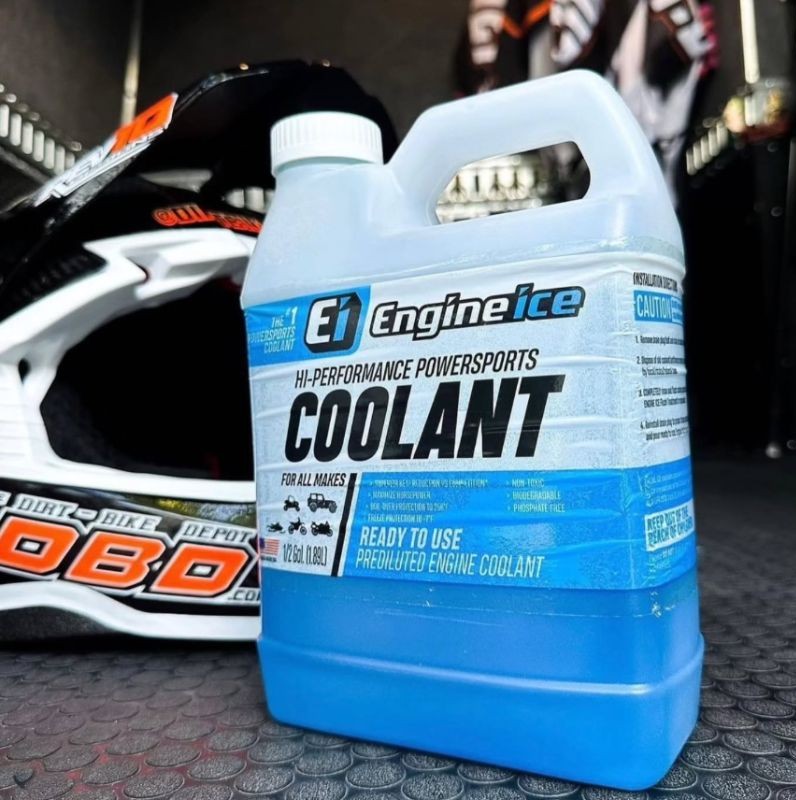 Engine Ice High Performance Coolant bottle next to a motocross helmet in a garage setup