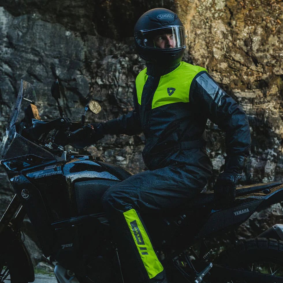 Rider wearing a laminated REV’IT! Pacific 4 H2O rain suit on a Yamaha Tenere, showcasing high-viz waterproof materials