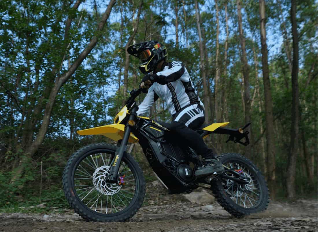 Rider on a Freego N5 electric dirt bike navigating a forest trail