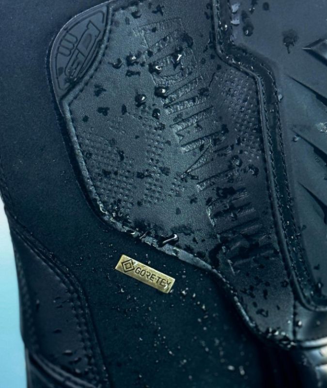 Close-up of a motorcycle boot with Gore-Tex waterproof membrane and water droplets beading on the surface.