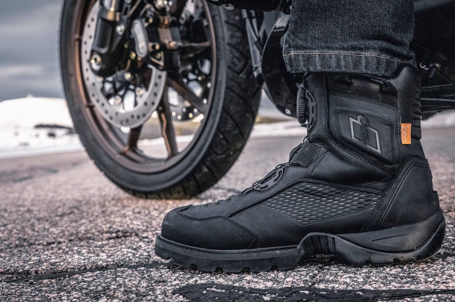 Icon Stormhawk WP motorcycle boots with BOA lacing system, D3O ankle inserts, and eVent waterproof liner on a rider by the road.