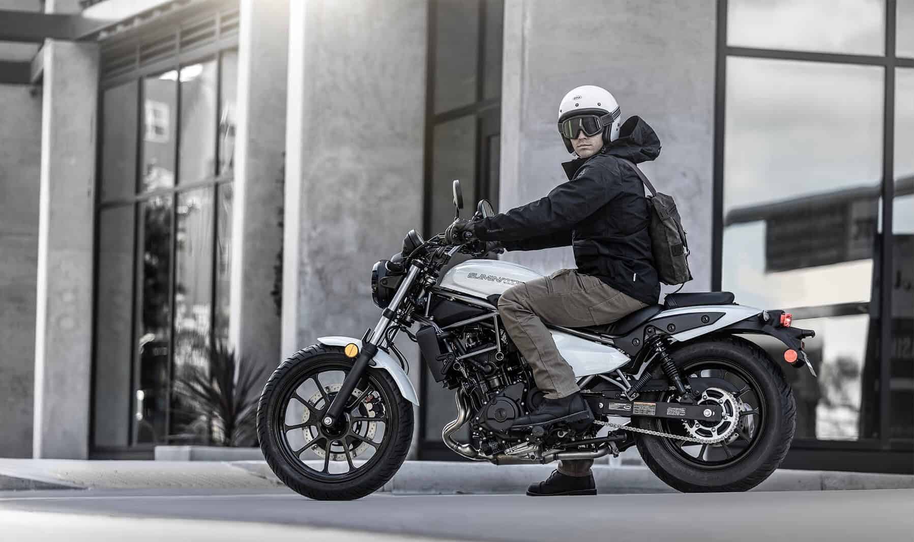 Rider on a white Kawasaki Eliminator cruiser stopped by an urban building