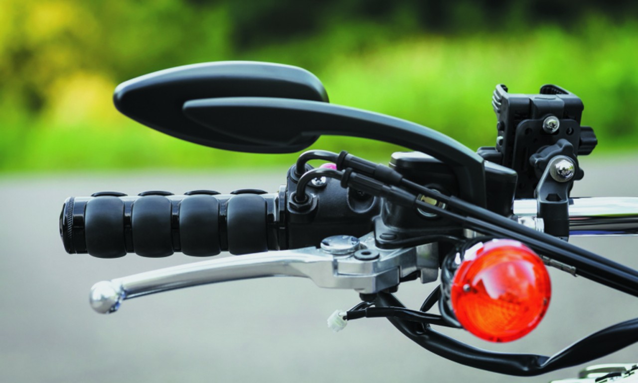 Close-up of Kuryakyn ISO grips on a cruiser handlebar with chrome accents and rubber pads for vibration damping.