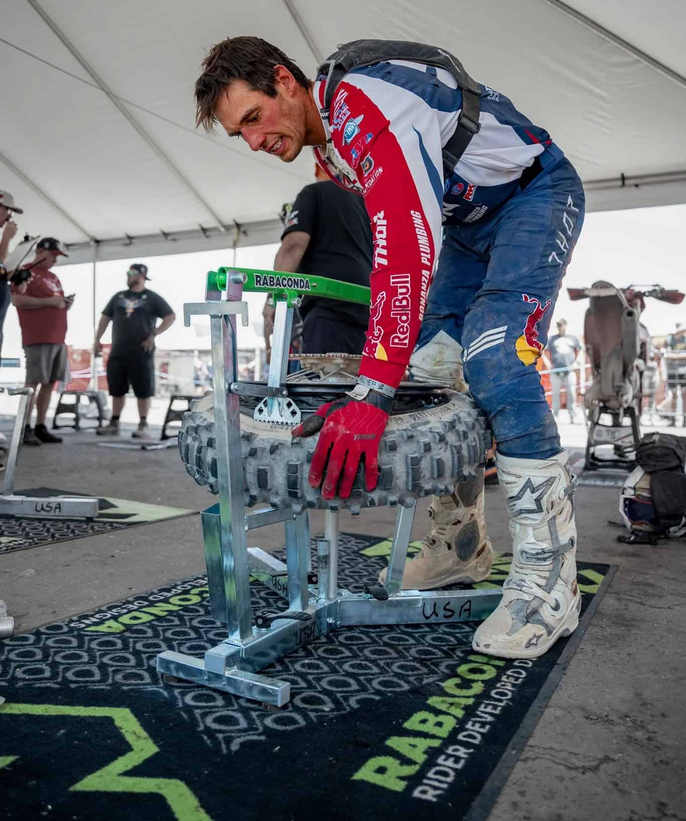 Off-road racer using the Rabaconda Dirt Bike Tire Changer to mount a mousse insert during a motocross event.