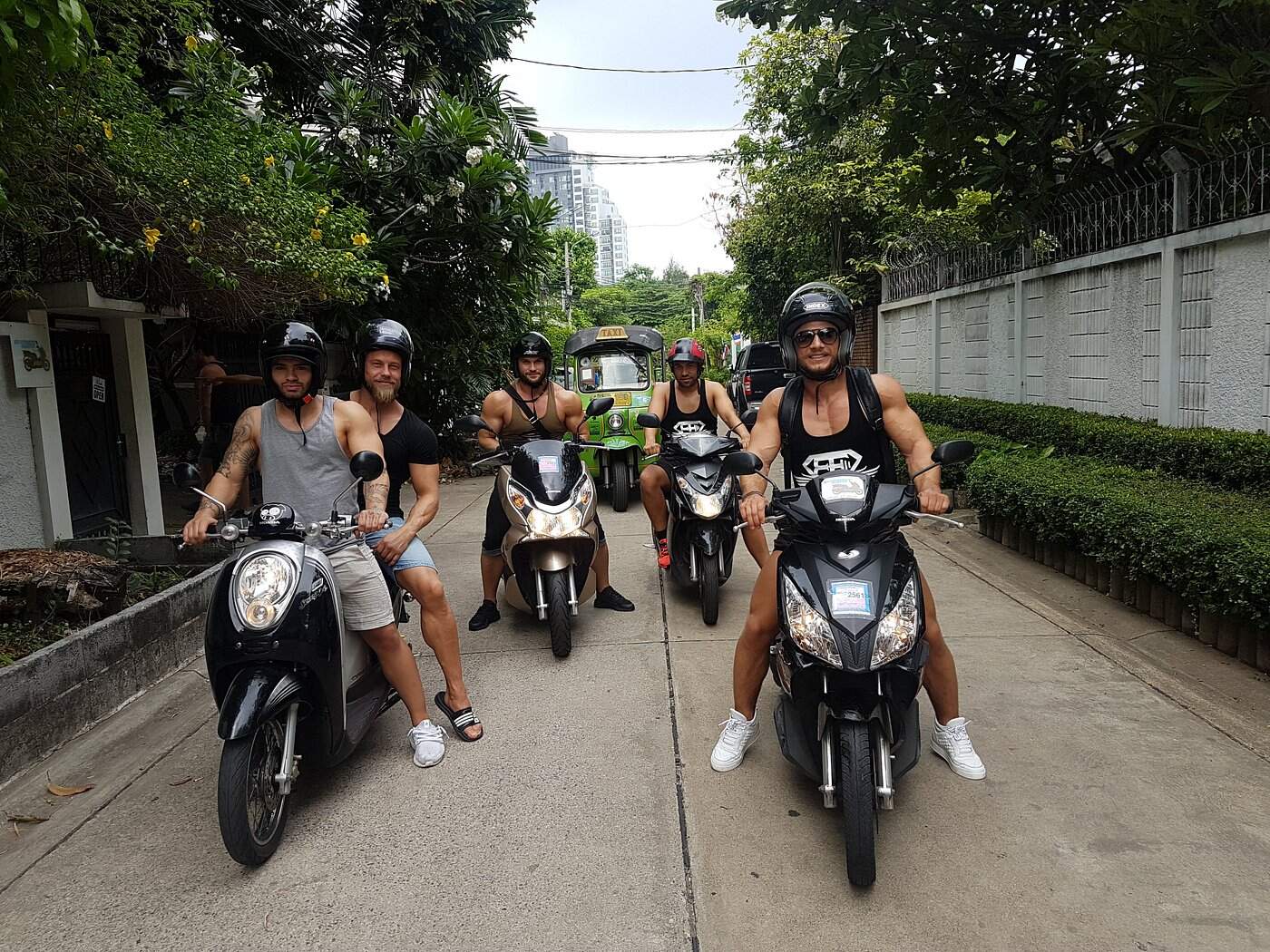 Group of riders on scooters exploring a quiet Bangkok street, representing Rent A Scooter Bangkok’s easy rentals for city travelers