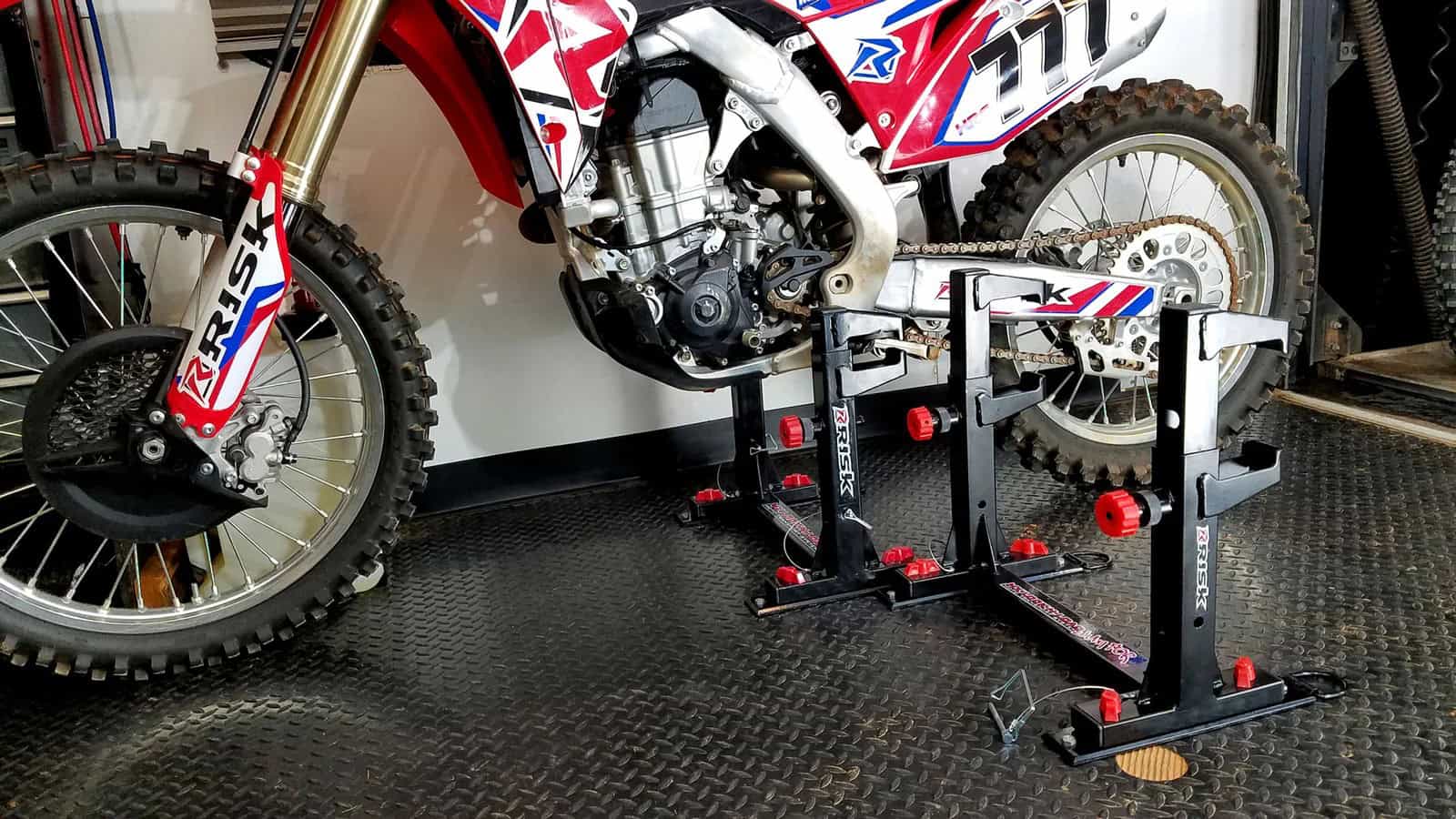 Motocross bike secured by footpegs in a Risk Racing Lock-N-Load Anchoring System inside a trailer, with floor space left open.