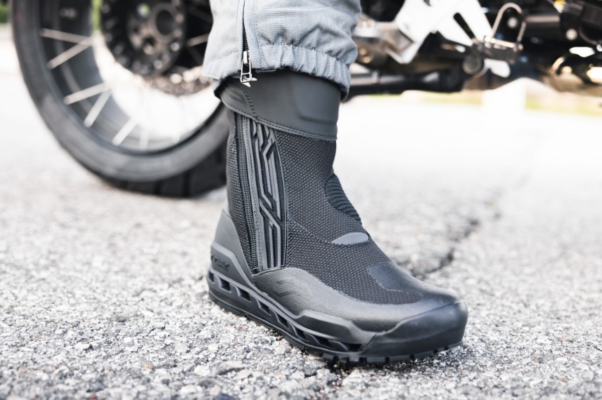 Close-up of TCX Clima 2 Surround GTX boots beside a motorcycle, highlighting their breathable Gore-Tex design and vented sole.