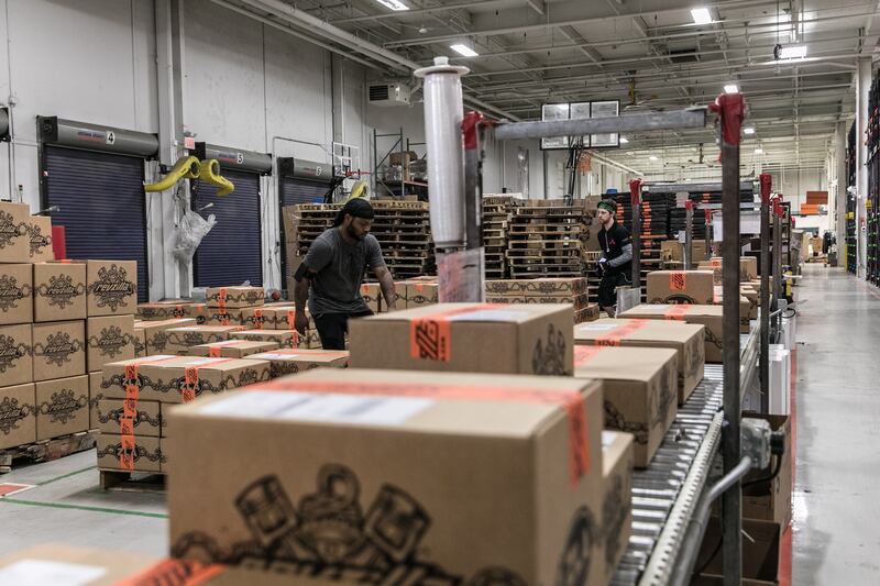 RevZilla warehouse workers preparing and packaging motorcycle gear boxes for fast shipping and order fulfillment.