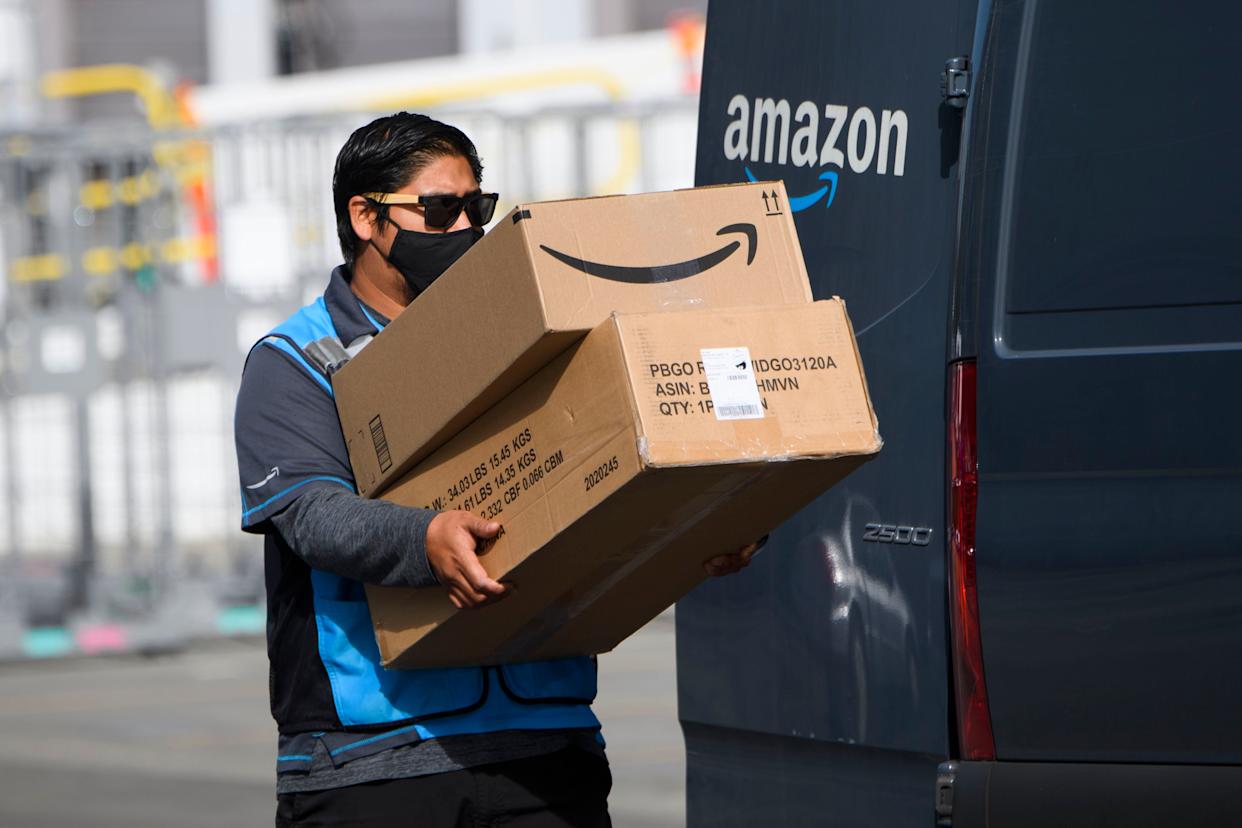 Amazon delivery driver carrying large boxes from a delivery van, representing fast Prime shipping service.