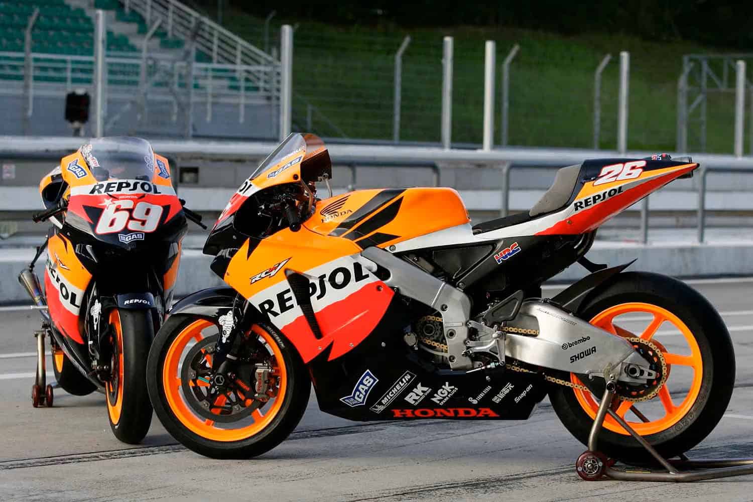 Two Repsol Honda race bikes on track stands showing lightweight chains