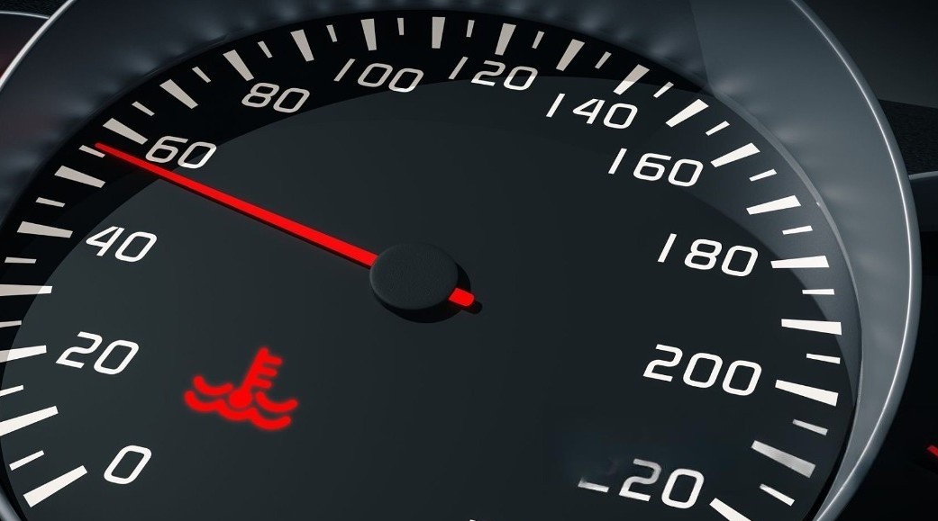 Close-up of a motorcycle dashboard with a glowing red engine temperature warning light