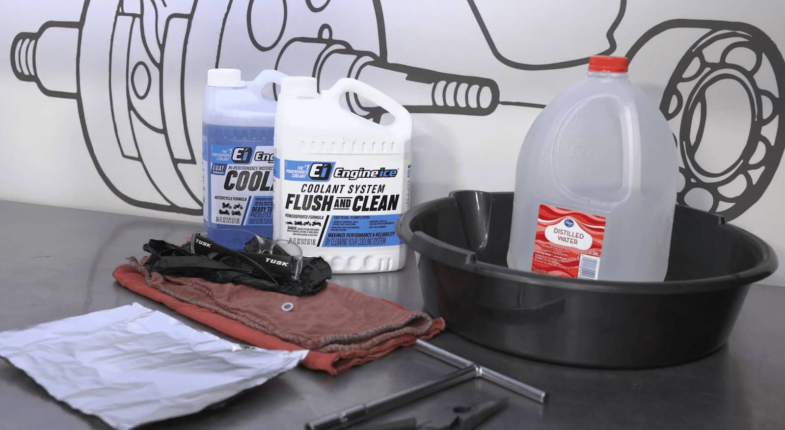 Coolant system flush setup with Engine Ice bottles, distilled water, and tools on a workbench