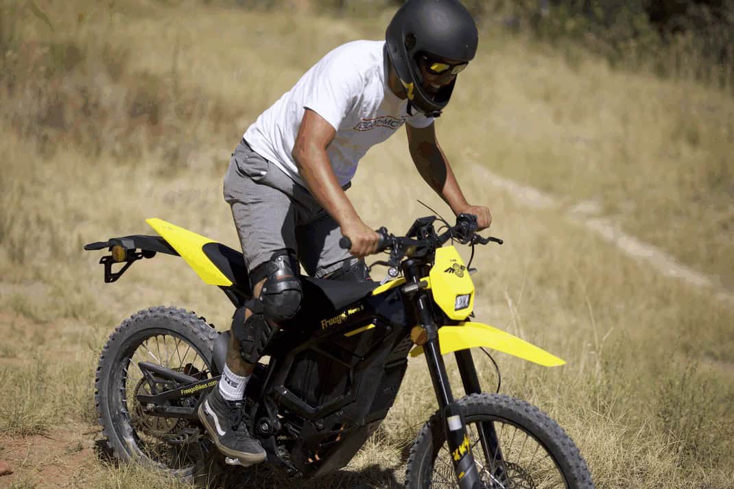 Rider on a yellow Freego N5 electric dirt bike climbing a dry off-road trail