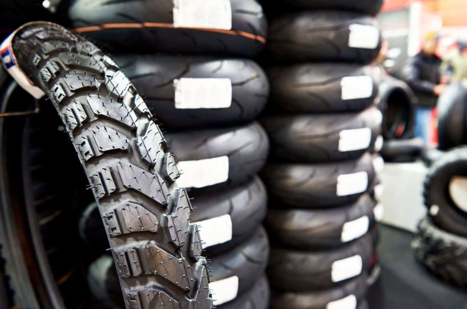 Stack of motorcycle tires in a shop display, showing tread patterns and variety of street and adventure tires.