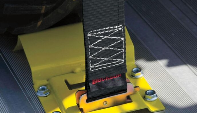 Close-up of a Moose Racing Wheel Chock & Tie-Down Strap Kit showing a heavy-duty strap secured to a yellow metal base plate.