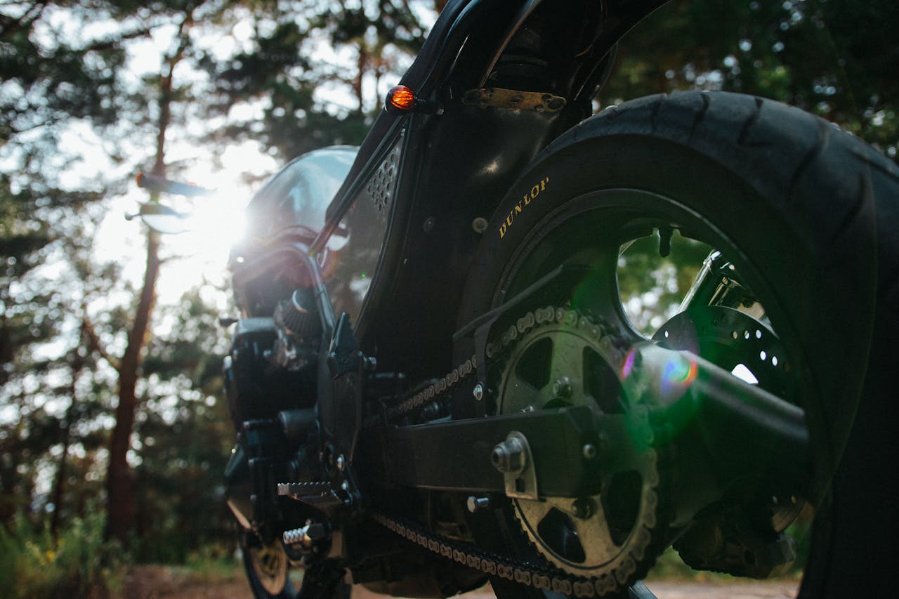 Close-up of a motorcycle rear wheel and chain in sunlight