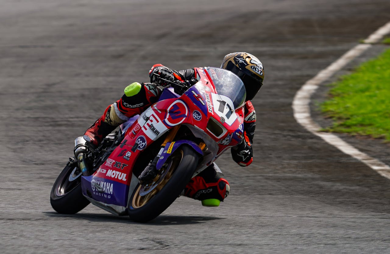 Motorcycle racer leaning into a high-speed corner on a sportbike, showcasing the importance of protective race gear and fit.
