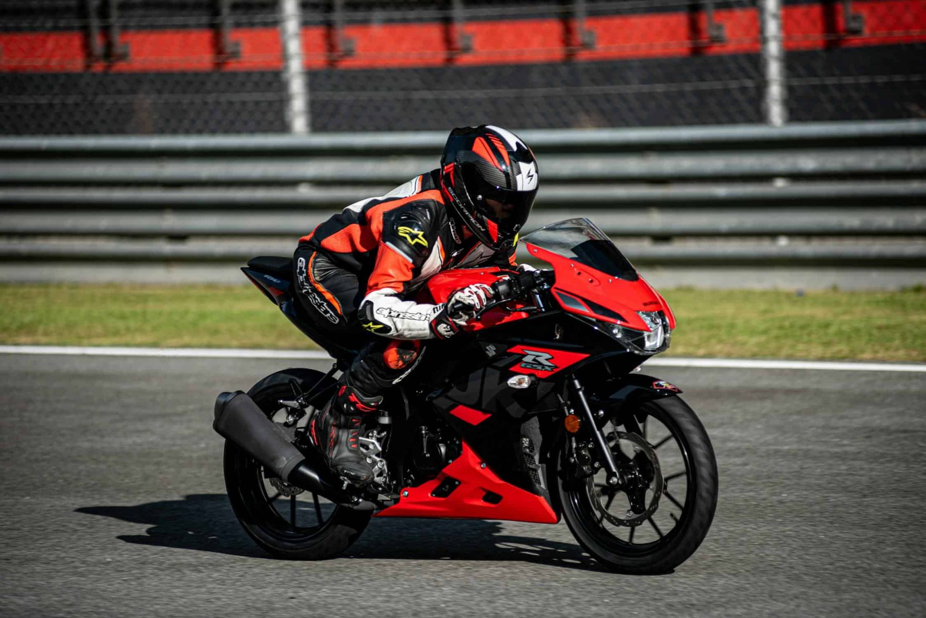 Motorcyclist in full racing gear leaning into a corner on track, showcasing the importance of proper race-ready boots for protection.