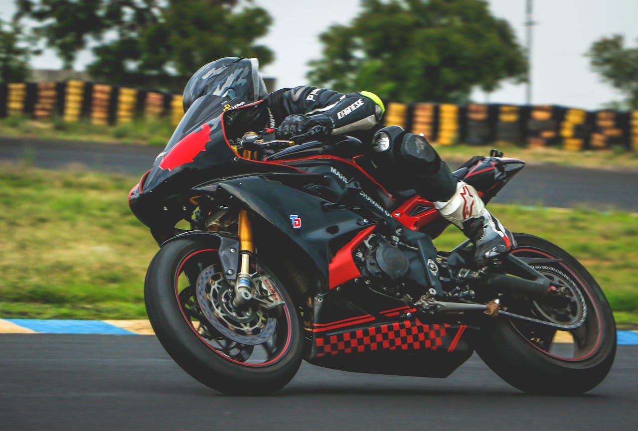 Motorcyclist in full racing gear leaning into a corner on a track, illustrating the importance of proper race suit fit and mobility.