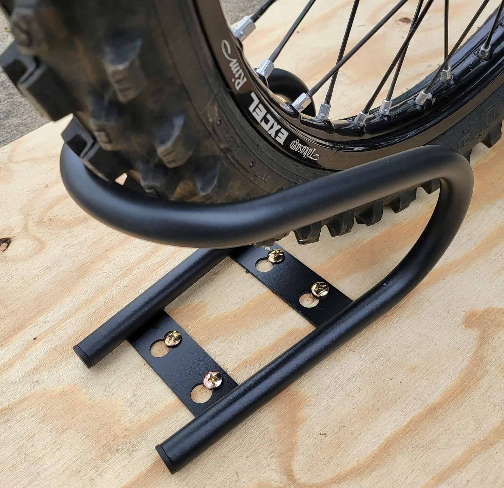 Close-up of a motorcycle tire secured in a Stockton Trailer 5.5" Wheel Chock mounted on a wooden trailer floor.