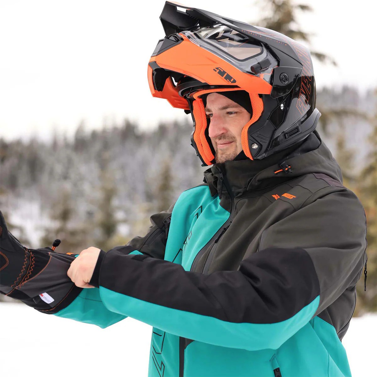 Rider wearing the 509 R-200 Insulated Crossover Jacket and modular snowmobile helmet in snowy conditions