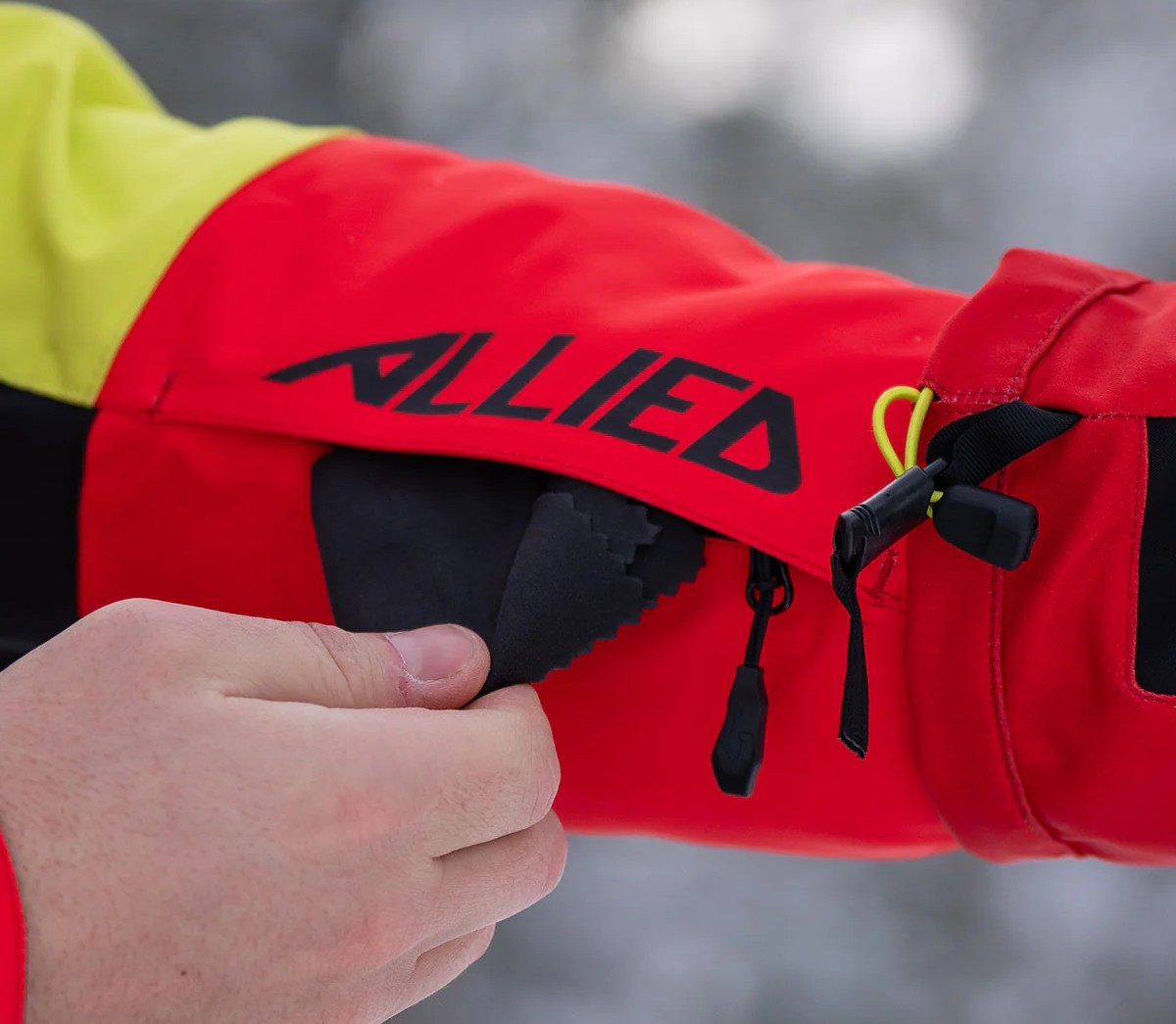 Close-up of a rider using the goggle wipe pocket on a 509 Allied snowmobile jacket
