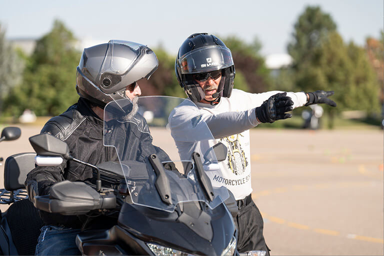 Motorcycle instructor guiding a rider during a safety training course