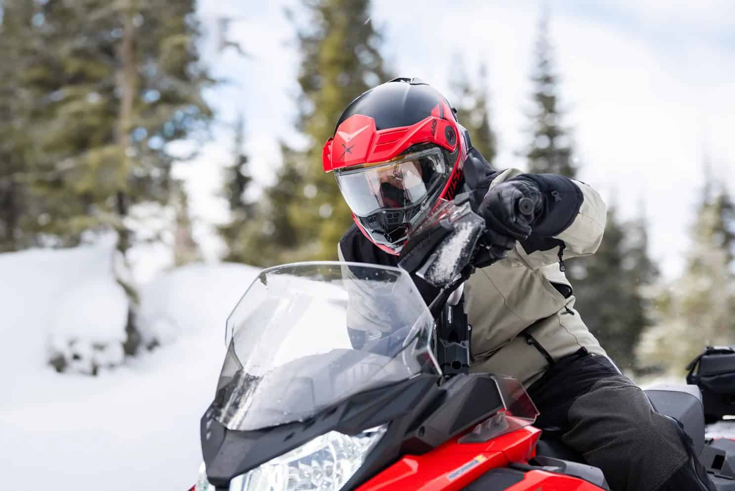 Rider wearing a CKX Mission Carbon modular snowmobile helmet while carving through snowy terrain